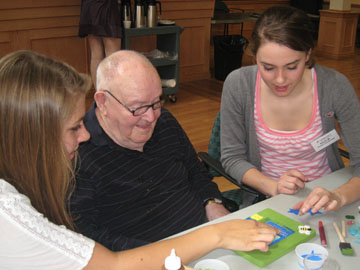 Students and a senior create a masterpiece Intergenerational volunteers decorate a picture frame