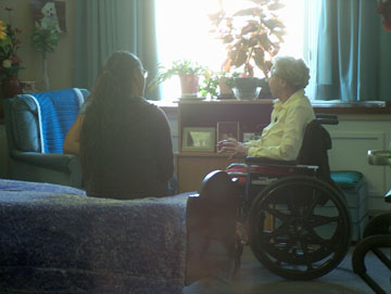 Two students visiting their senior friend Intergenerational program volunteers visit with each other
