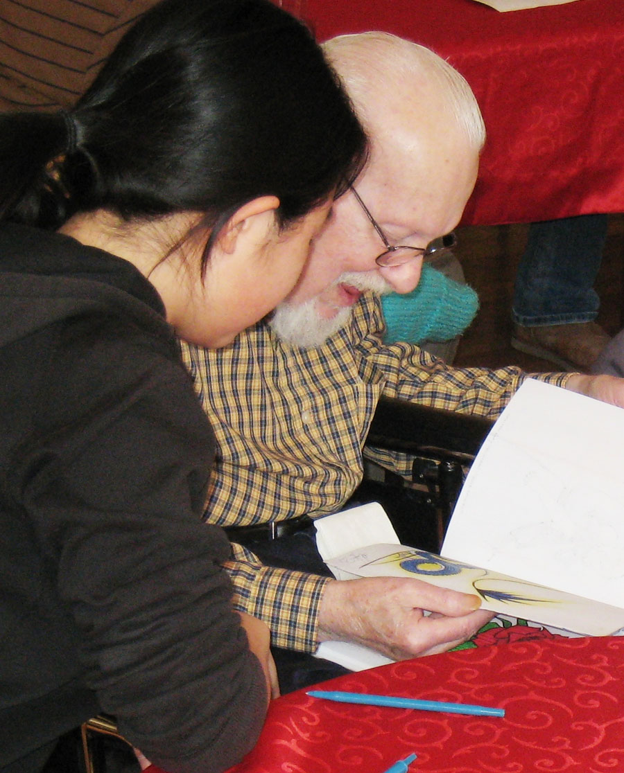 A senior high student and her senior partner reading Intergenerational program volunteers reading a book